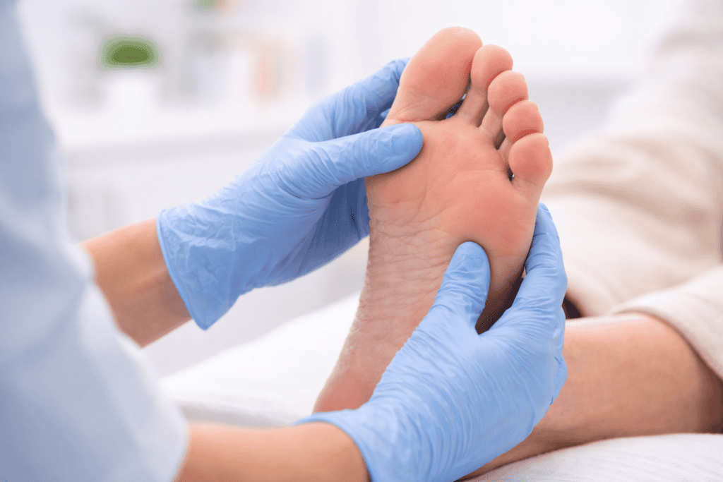 Healthcare professional examining a patient's foot wearing blue medical gloves